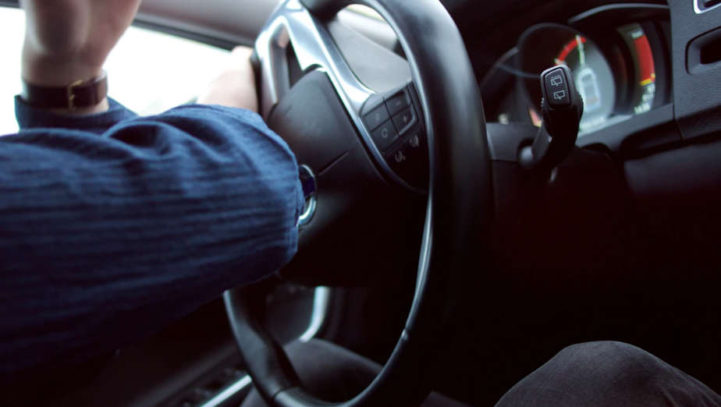 man turning a car steering wheel